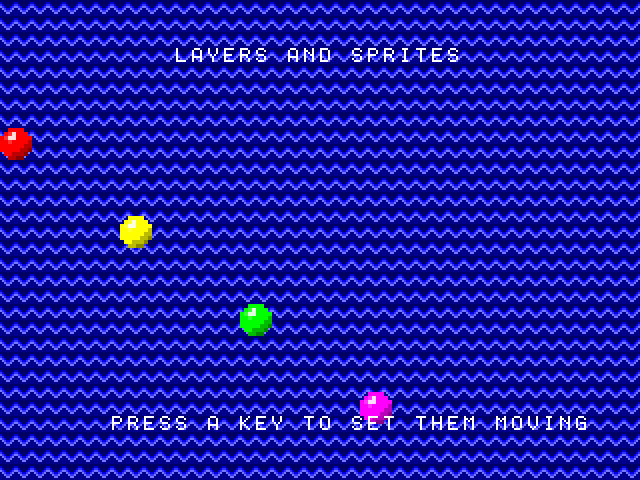 A blue screen of zigzag waves with LAYERS AND SPRITES in white at the top, four shaded balls — red, yellow, green and magenta — scattered down it, and PRESS A KEY TO SET THEM MOVING in white along the bottom, passing in front of the magenta ball.